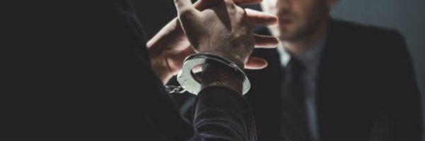 Criminal man with handcuffs being interviewed in interrogation room after committed a crime