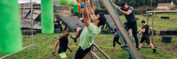 Male participant in an obstacle course doing suspension ring exercises