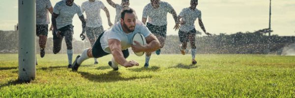 Full length shot of a handsome young rugby player scoring a try while training on a rainy day