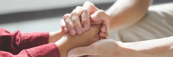 Close-up of man psychologist or psychiatrist sitting and holding hands palm of his woman patient for encouragement. PTSD Mental health concept,