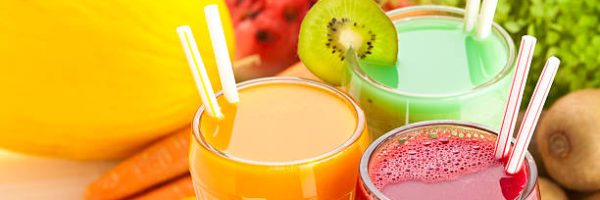 Close Up of Three Glasses of Fruit Juices on White Garden Table. High Angle View.